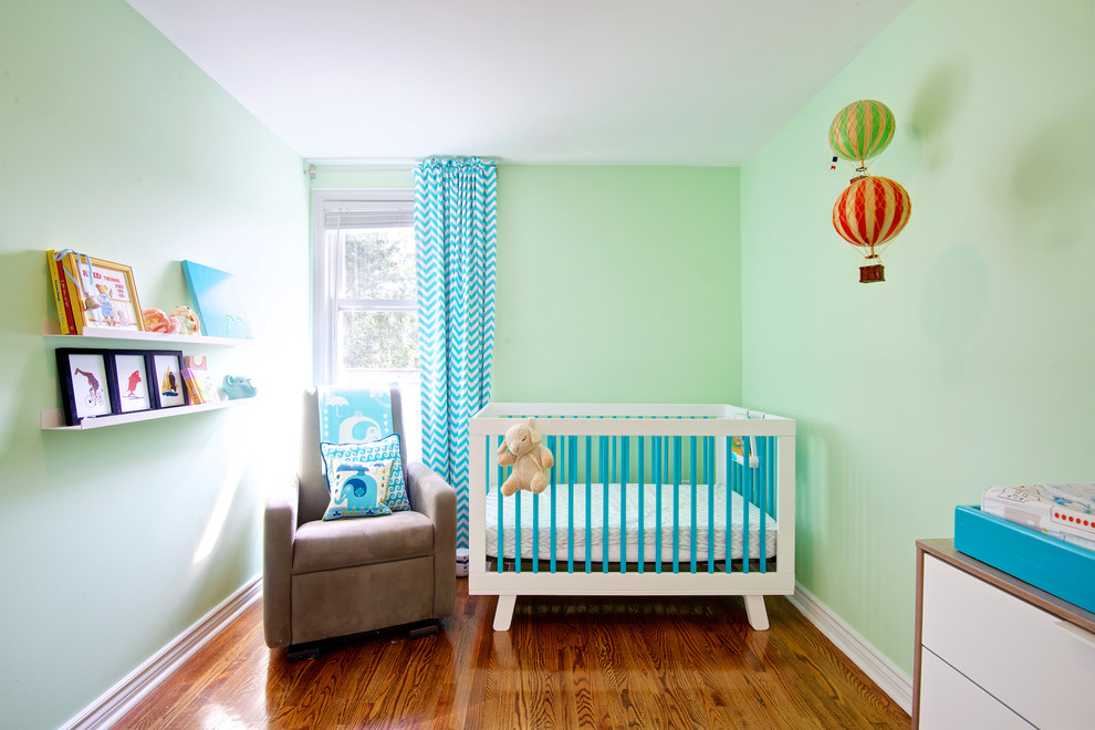 Cette image montre une petite chambre de bébé design avec un mur vert et un sol en bois brun.