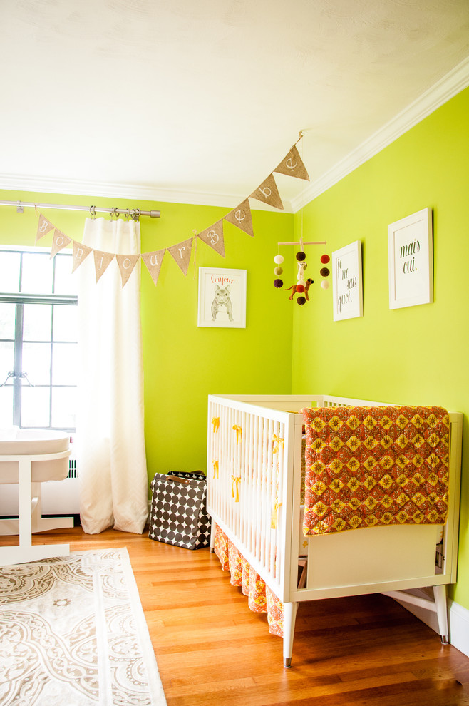 Réalisation d'une chambre de bébé neutre bohème avec un mur vert, un sol en bois brun et un sol orange.