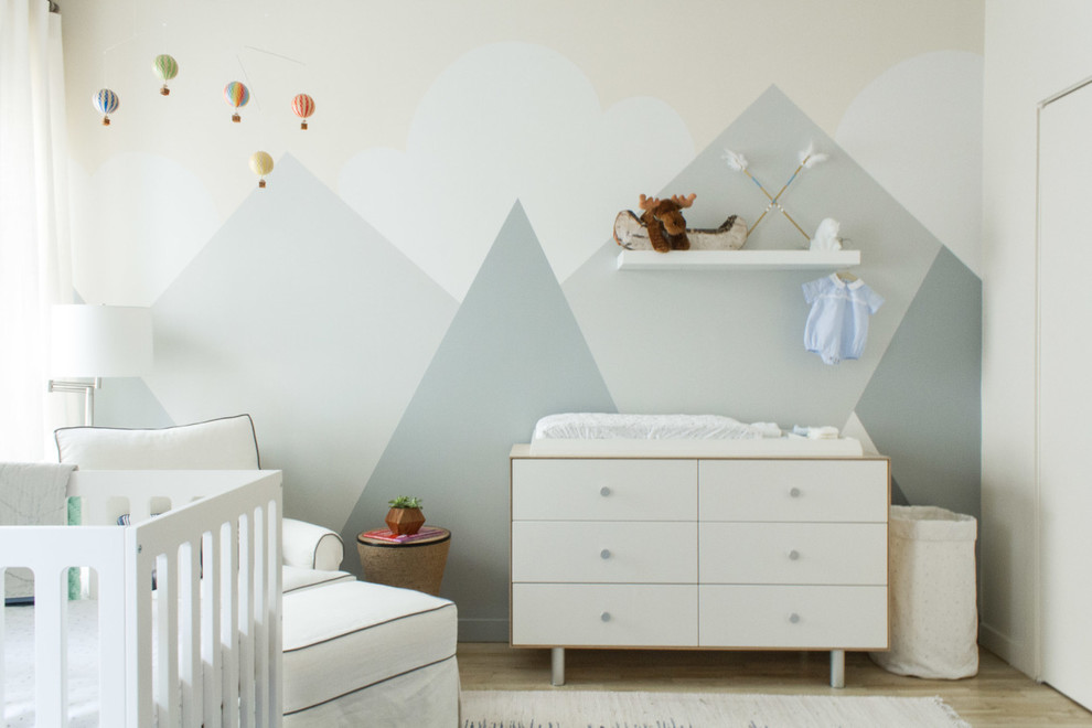Cette image montre une chambre de bébé garçon design de taille moyenne avec un mur beige et un sol en bois brun.