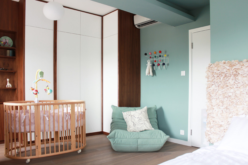 Cette image montre une chambre de bébé neutre minimaliste avec un mur bleu et un sol en bois brun.