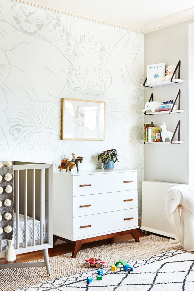 Réalisation d'une chambre de bébé tradition avec un mur blanc, un sol en bois brun, un sol marron et du papier peint.