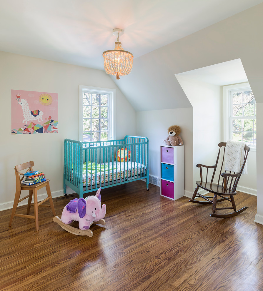 Example of a mid-sized eclectic gender-neutral medium tone wood floor nursery design in Minneapolis with white walls