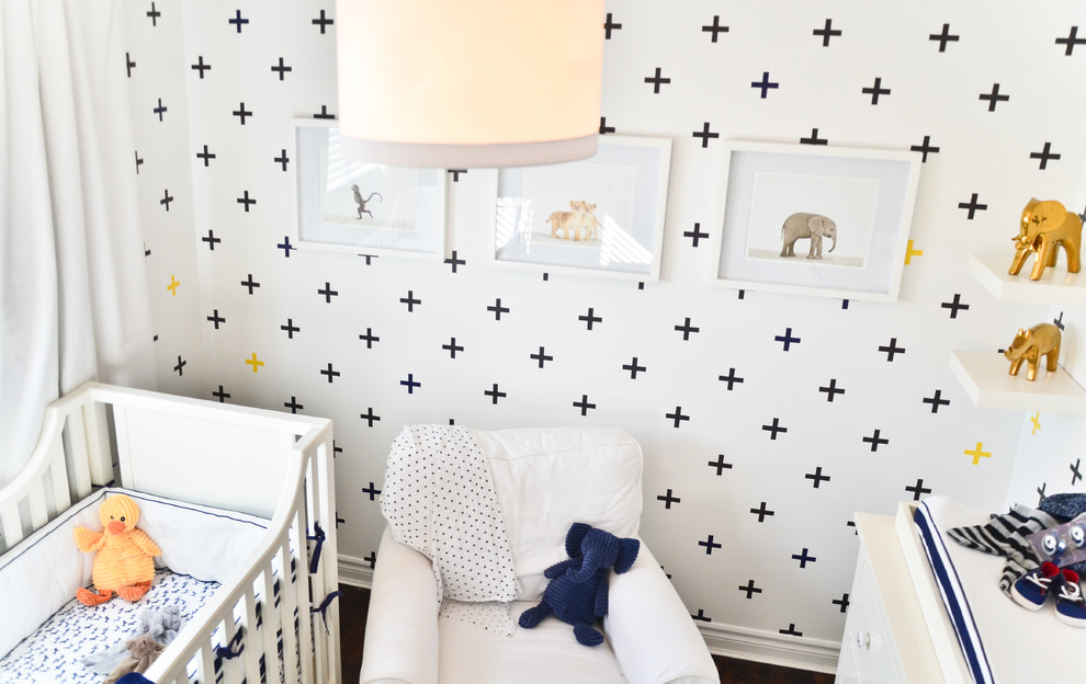 Ejemplo de habitación de bebé neutra actual pequeña con paredes blancas y suelo de madera oscura