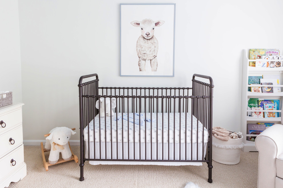 Modelo de habitación de bebé neutra tradicional de tamaño medio con paredes blancas, moqueta y suelo beige