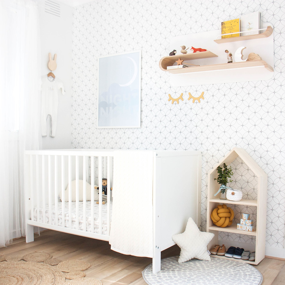 Medium sized scandinavian gender neutral nursery with light hardwood flooring, beige floors and white walls.