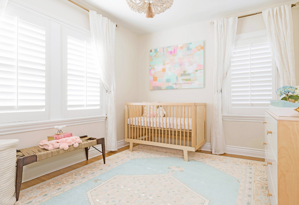 Inspiration for a small bohemian nursery for girls in Los Angeles with beige walls and light hardwood flooring.