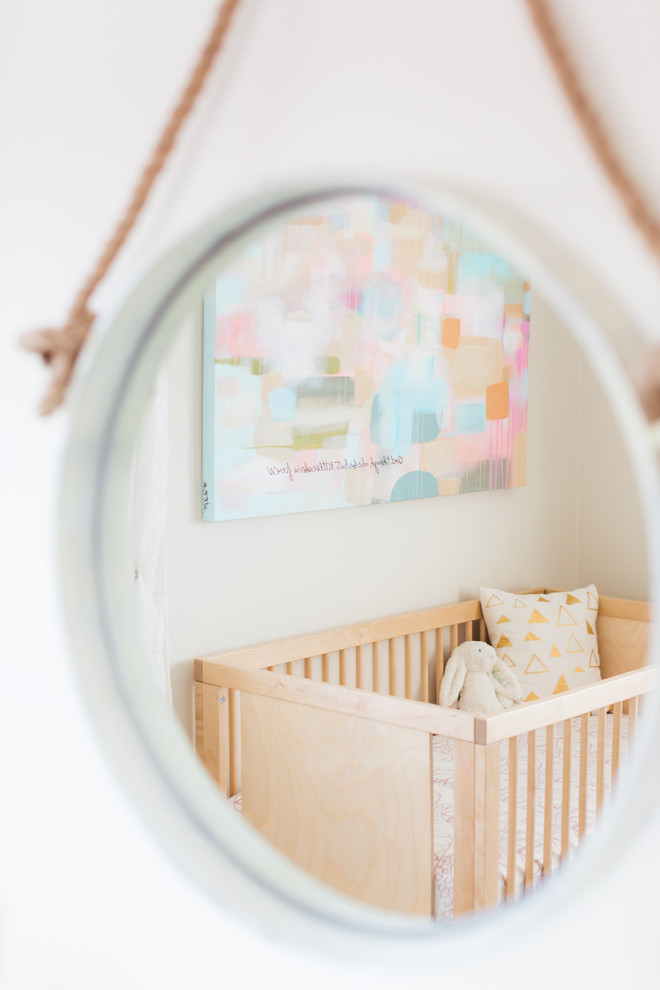 Photo of a small bohemian nursery for girls in Los Angeles with beige walls and light hardwood flooring.