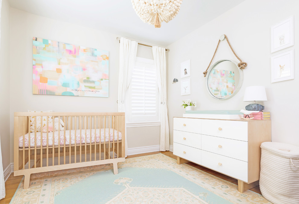 Photo of a small classic nursery for girls in Los Angeles with beige walls and light hardwood flooring.