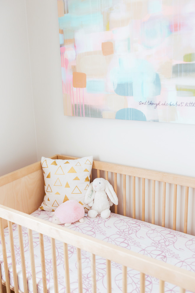 Small bohemian nursery for girls in Los Angeles with beige walls and light hardwood flooring.