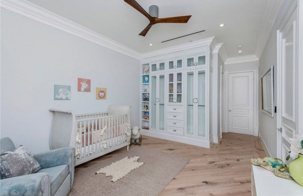 Cette image montre une grande chambre de bébé neutre traditionnelle avec un mur gris, parquet clair et un sol beige.