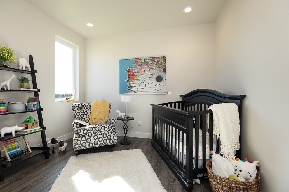 Cette image montre une petite chambre de bébé neutre traditionnelle avec sol en stratifié, un mur gris et un sol marron.