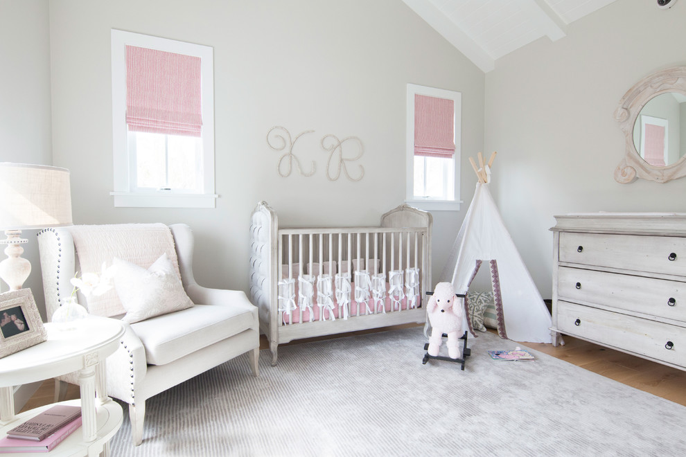 Immagine di una cameretta per neonata country di medie dimensioni con pareti beige e parquet chiaro