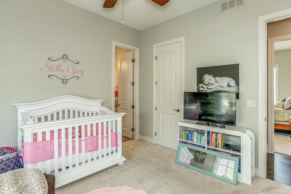 Modelo de habitación de bebé niña tradicional renovada de tamaño medio con paredes beige y moqueta