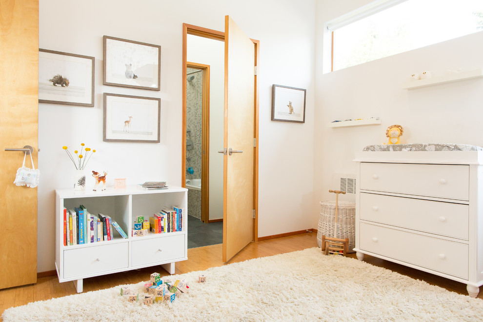 Imagen de habitación de bebé neutra escandinava pequeña con paredes blancas, suelo de bambú y suelo beige