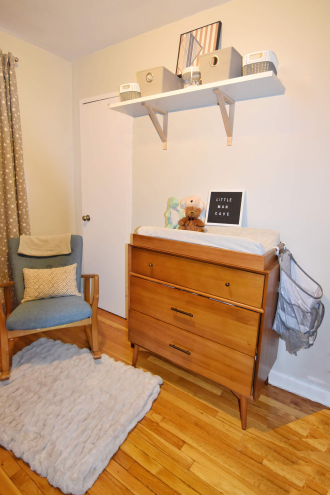 Kleines Retro Babyzimmer mit grauer Wandfarbe, hellem Holzboden und braunem Boden in New York