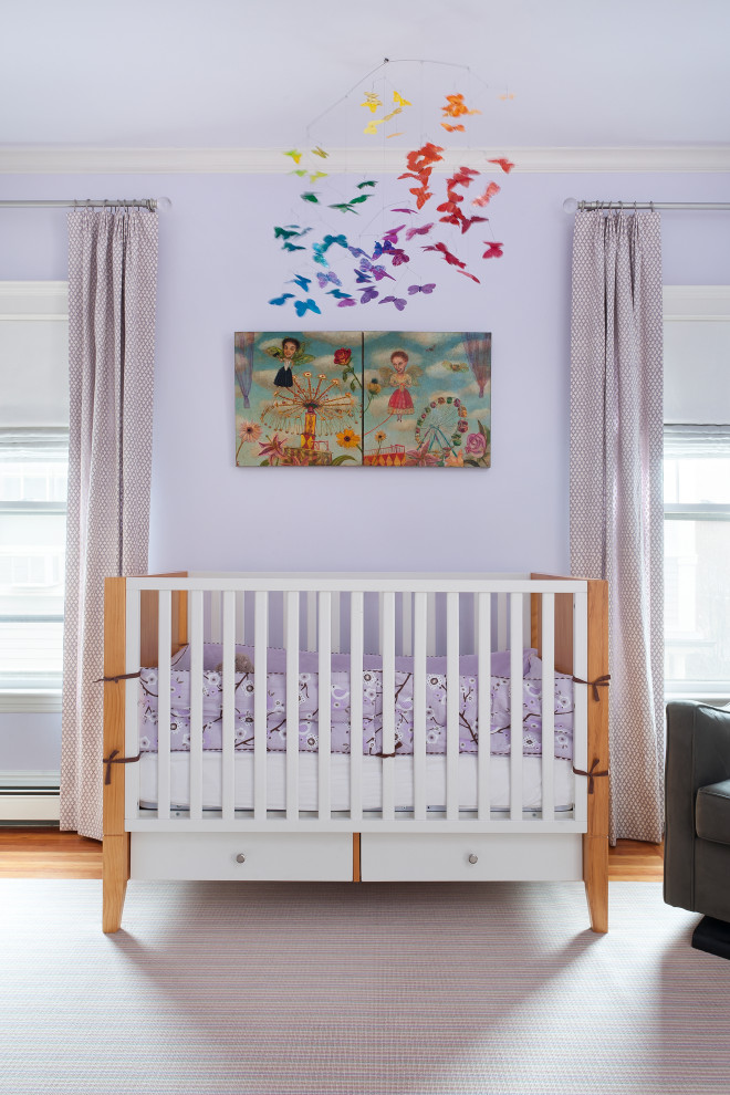 Exemple d'une chambre de bébé tendance avec un mur violet, un sol en bois brun et un sol marron.
