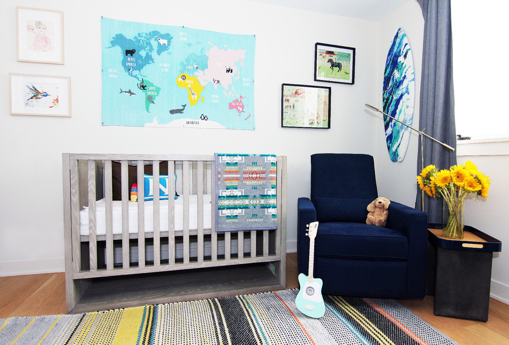 Cette photo montre une chambre de bébé tendance avec un mur blanc, un sol en bois brun et un sol marron.