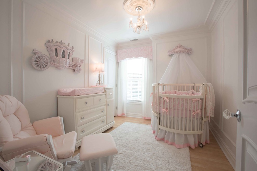 Modelo de habitación de bebé tradicional de tamaño medio con paredes blancas y suelo laminado