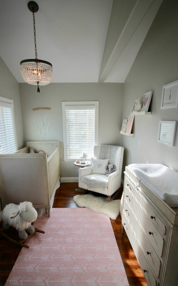 Aménagement d'une chambre de bébé fille contemporaine avec un mur gris et un sol en bois brun.