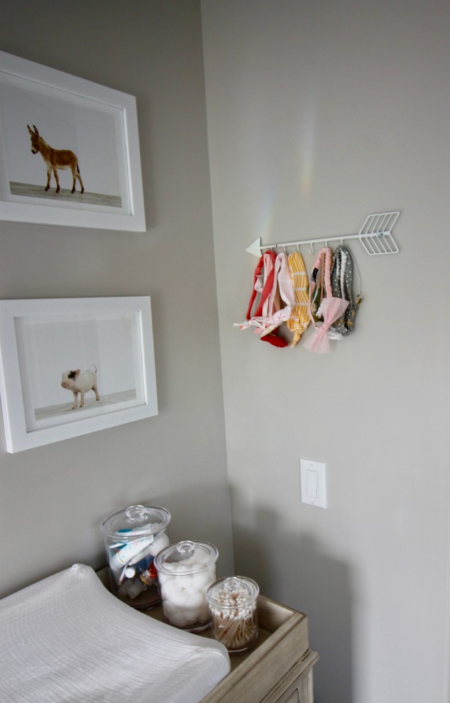 Immagine di una cameretta per neonata minimal con pareti grigie e pavimento in legno massello medio