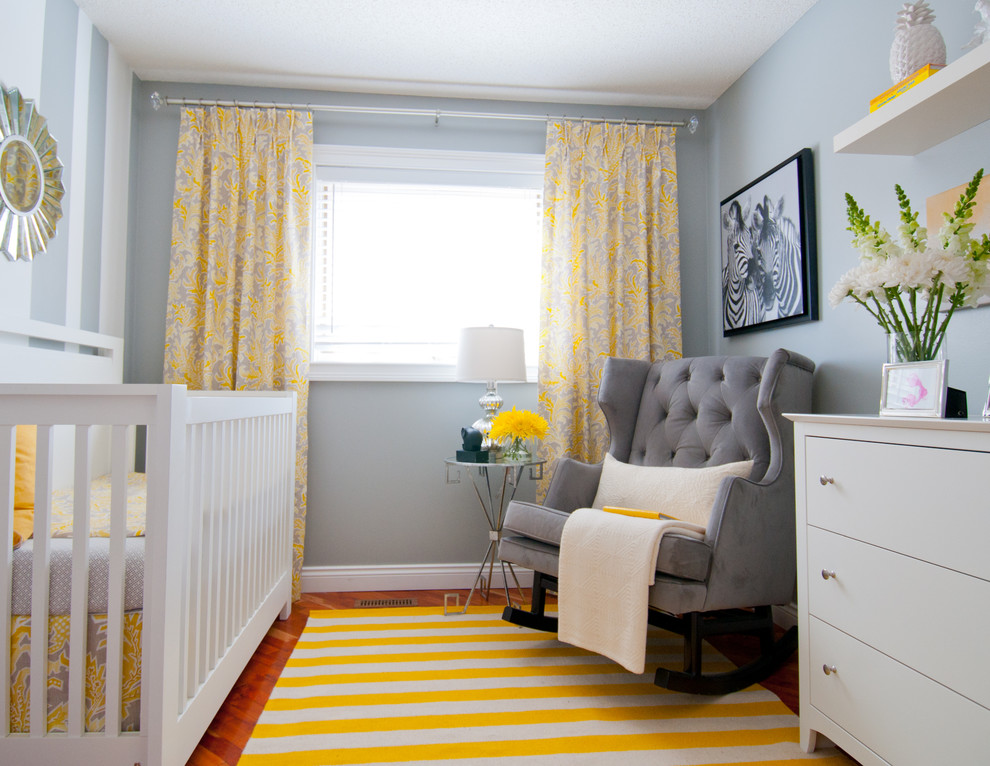 Diseño de habitación de bebé neutra clásica renovada pequeña con paredes grises y suelo de madera en tonos medios