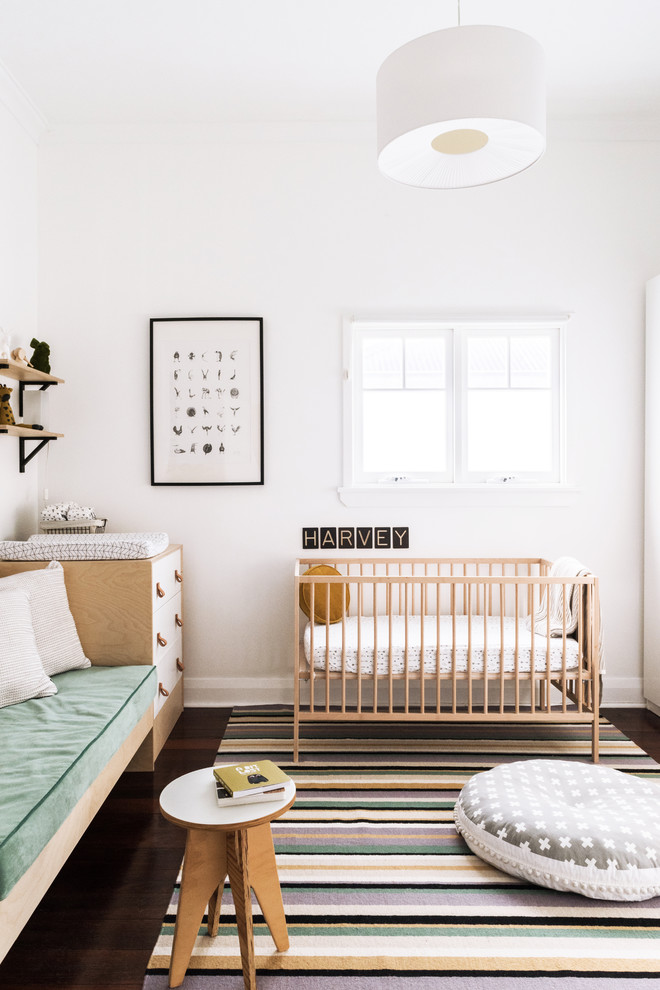 Idéer för ett litet modernt babyrum, med vita väggar, mörkt trägolv och brunt golv