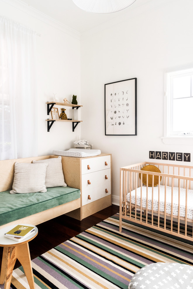 Imagen de habitación de bebé niño escandinava pequeña con paredes blancas, suelo de madera oscura y suelo marrón