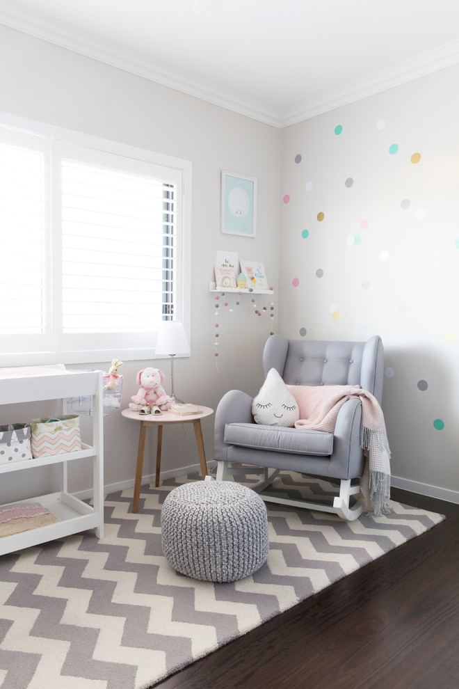 Réalisation d'une chambre de bébé fille design de taille moyenne avec un mur gris et parquet foncé.