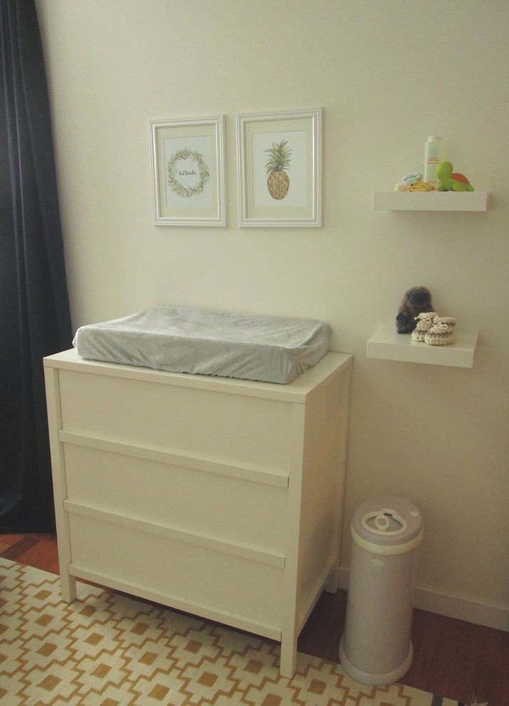 Modelo de habitación de bebé tradicional renovada pequeña con paredes blancas, suelo de madera en tonos medios y suelo marrón