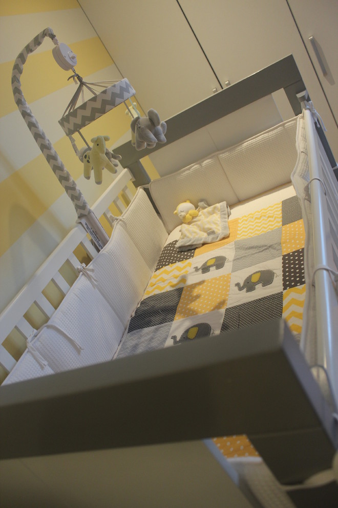 Idée de décoration pour une grande chambre de bébé neutre tradition avec un mur jaune, un sol en bois brun et un sol marron.