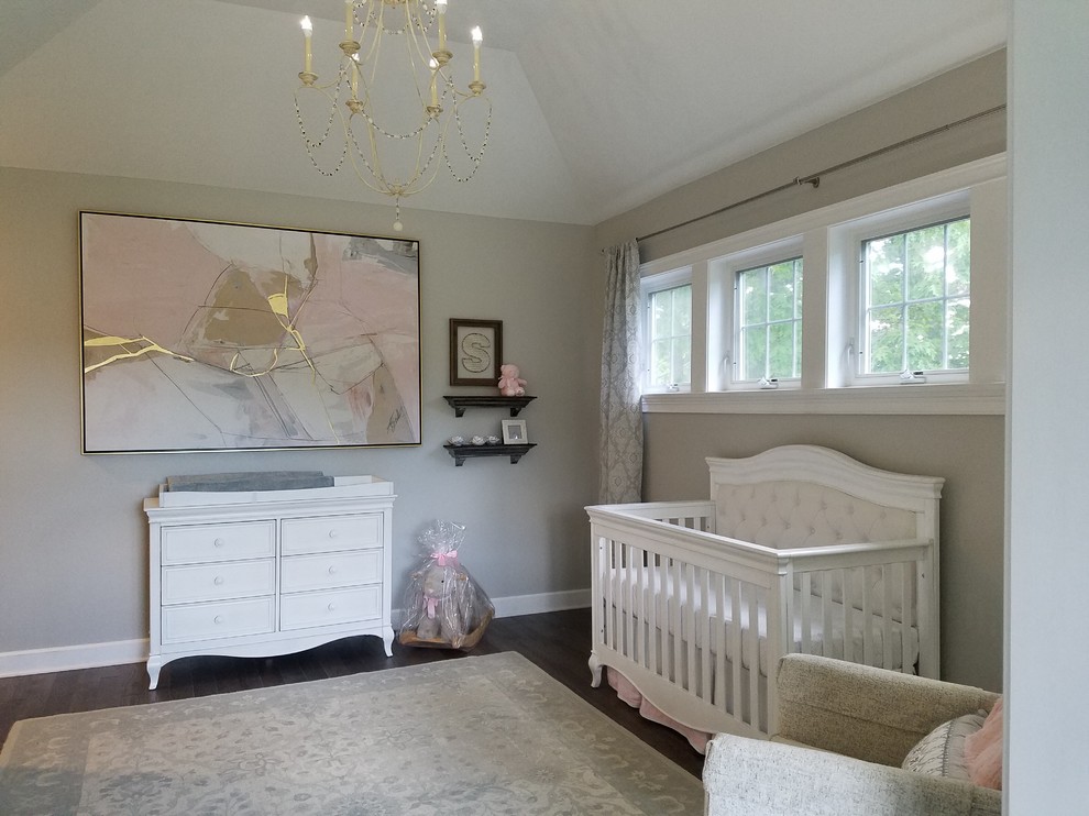 Immagine di una grande cameretta per neonata classica con pareti grigie, pavimento in legno massello medio e pavimento grigio