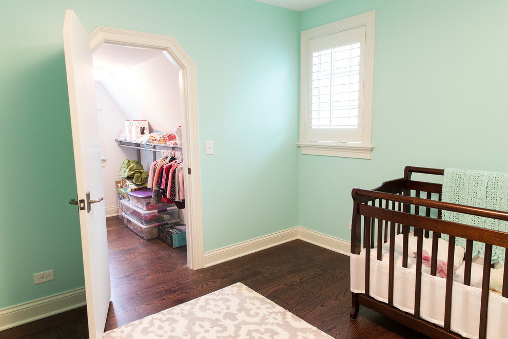 Cette image montre une chambre de bébé neutre traditionnelle de taille moyenne avec un mur vert, un sol en bois brun et un sol marron.