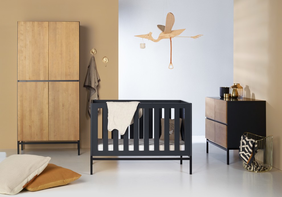 Imagen de habitación de bebé neutra actual de tamaño medio con paredes beige, suelo de cemento y suelo gris