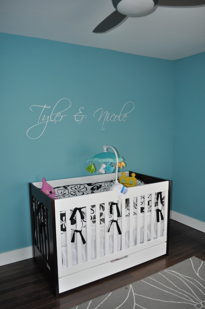 Inspiration pour une chambre de bébé neutre minimaliste avec un mur bleu et parquet foncé.