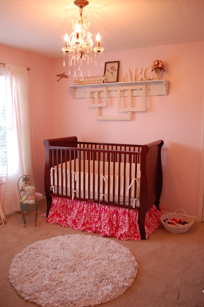 Foto di una cameretta per neonata tradizionale con pareti rosa e moquette