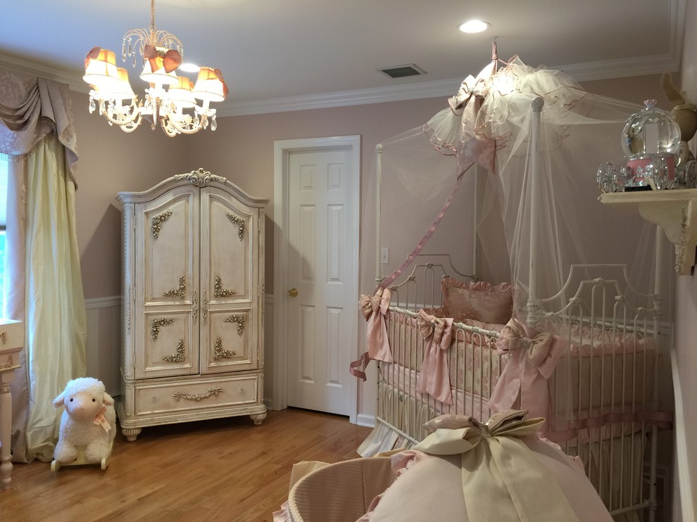Inspiration for a large shabby-chic style girl light wood floor nursery remodel in New York with pink walls
