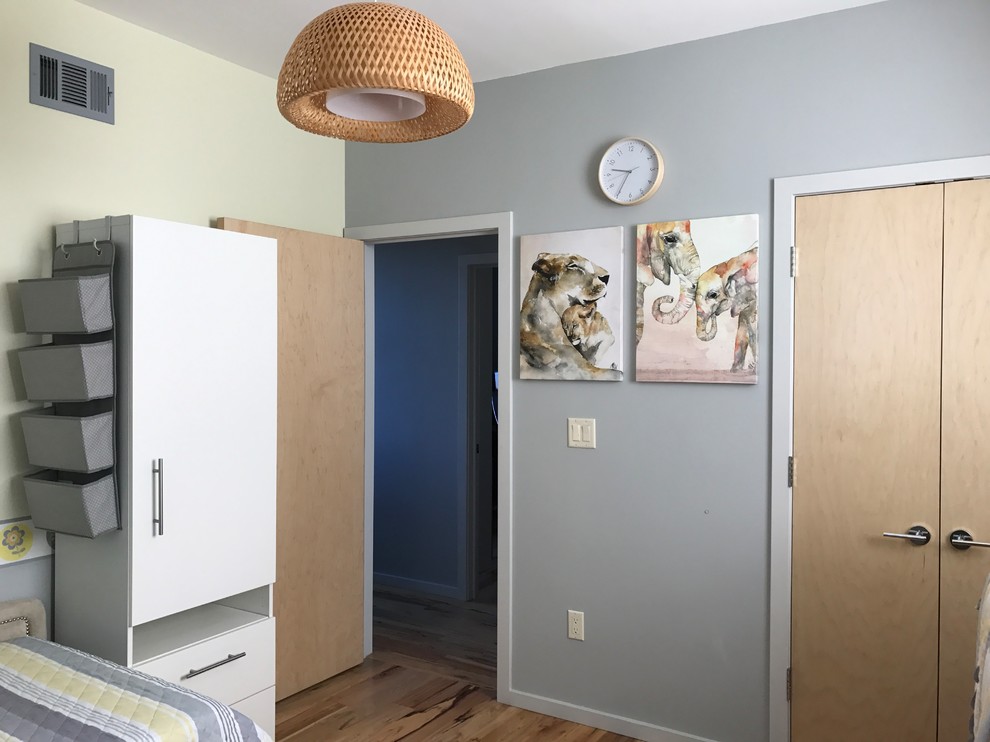 Photo of a medium sized modern gender neutral nursery in New York with yellow walls and light hardwood flooring.
