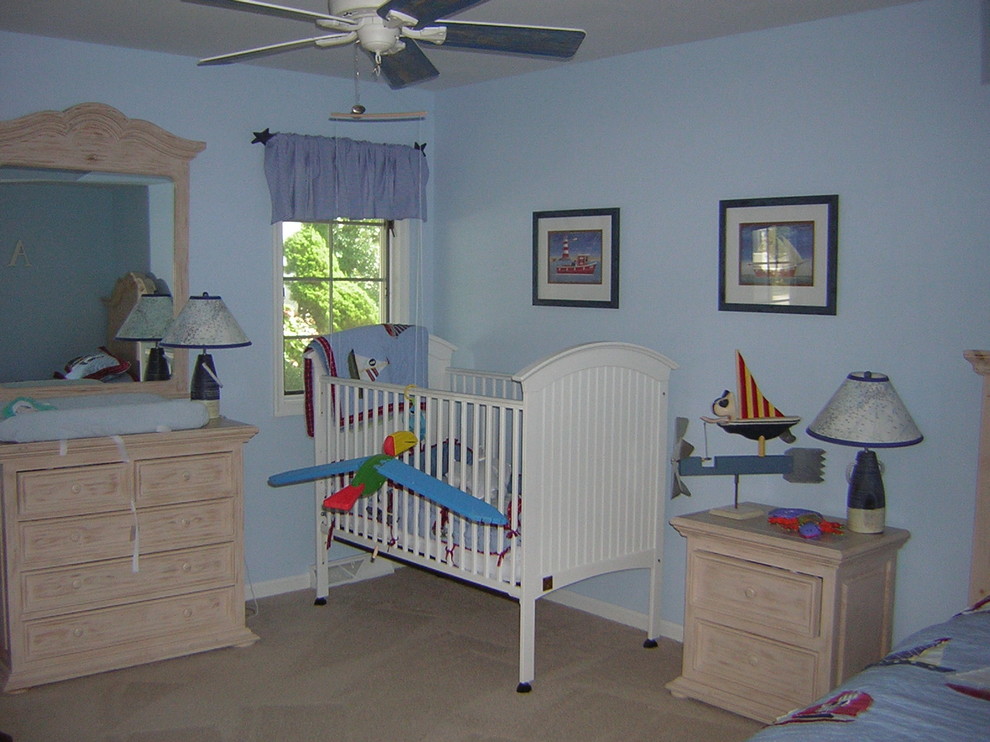 Modelo de habitación de bebé niño clásica renovada de tamaño medio con paredes azules, moqueta y suelo beige