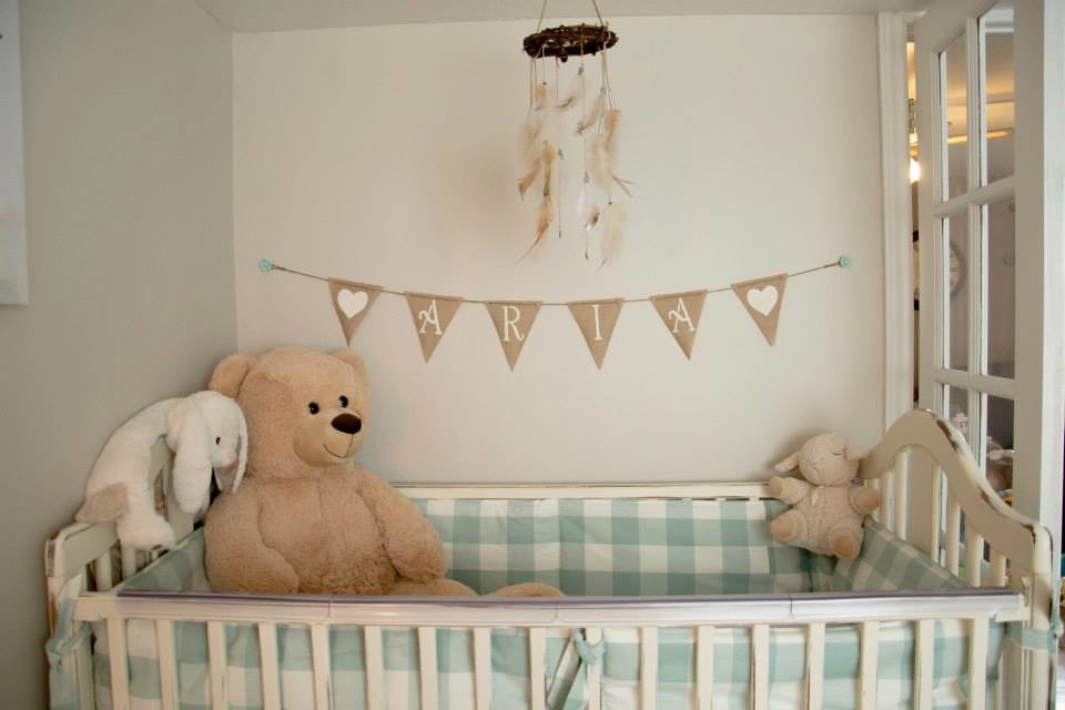 Modelo de habitación de bebé niña rural de tamaño medio con paredes beige y suelo laminado