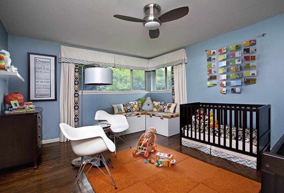 Modelo de habitación de bebé neutra contemporánea de tamaño medio con paredes azules y suelo de madera oscura