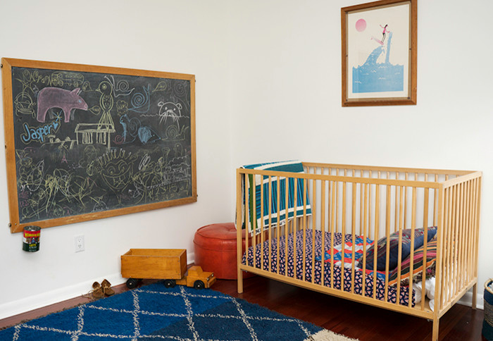 Immagine di una cameretta per neonata eclettica di medie dimensioni con pareti bianche, parquet scuro e pavimento marrone
