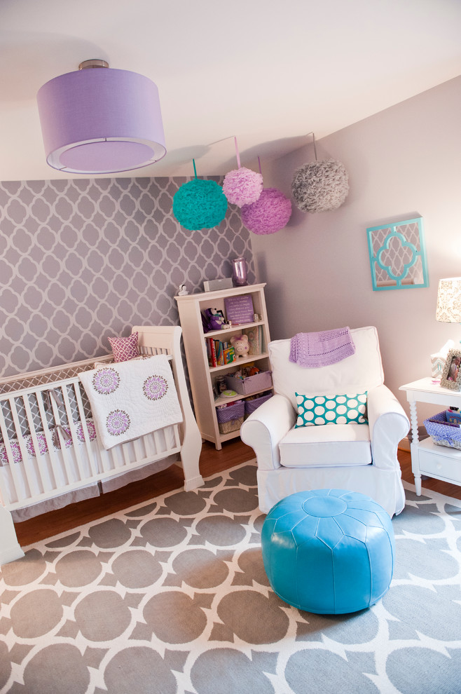 Idée de décoration pour une chambre de bébé design de taille moyenne avec un mur violet et un sol en bois brun.