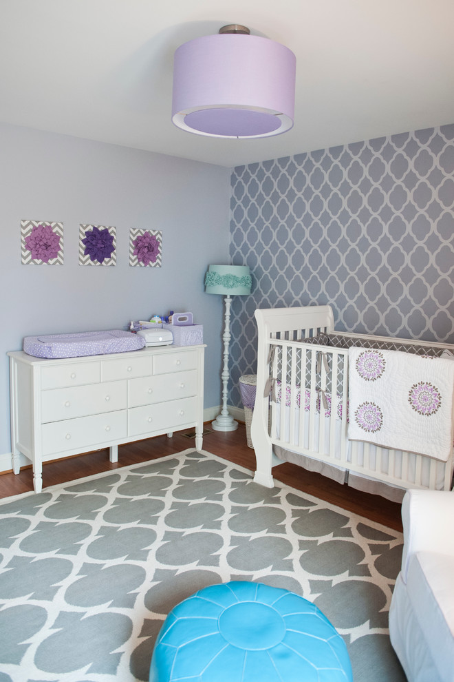 Idée de décoration pour une chambre de bébé tradition de taille moyenne avec un mur violet et un sol en bois brun.