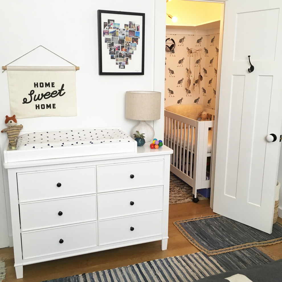 Cette photo montre une petite chambre de bébé tendance avec un mur blanc et parquet clair.