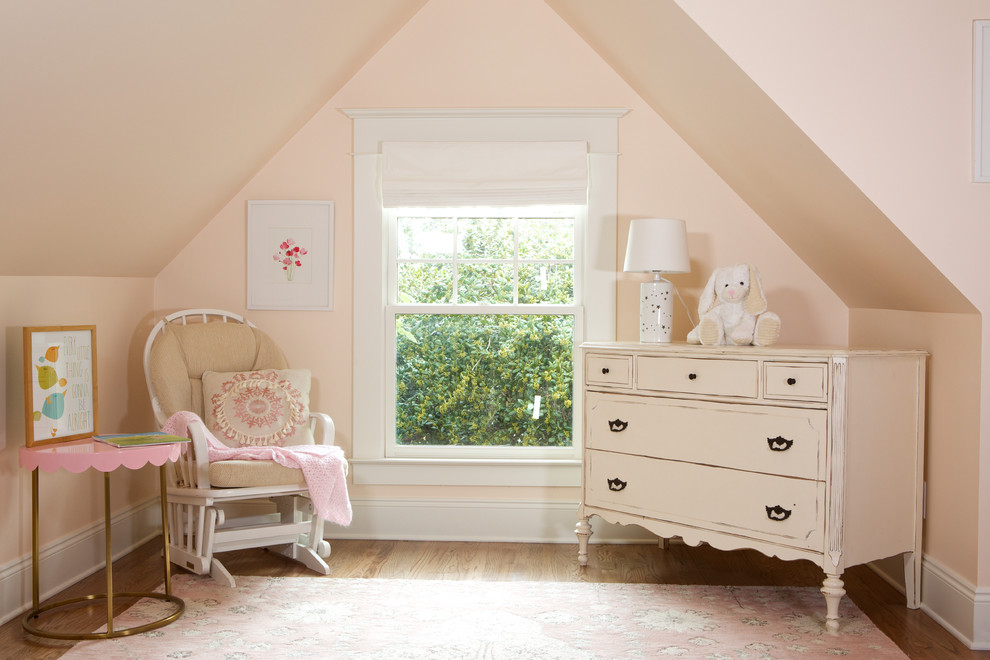 Cette image montre une chambre de bébé fille rustique de taille moyenne avec un mur rose, un sol en bois brun et un sol marron.