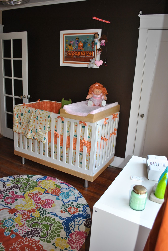 Exemple d'une chambre de bébé neutre moderne avec un mur marron et parquet foncé.