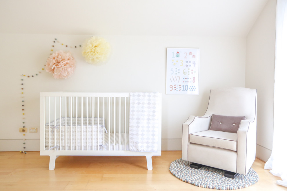 Modelo de habitación de bebé neutra actual de tamaño medio con paredes blancas y suelo de madera clara