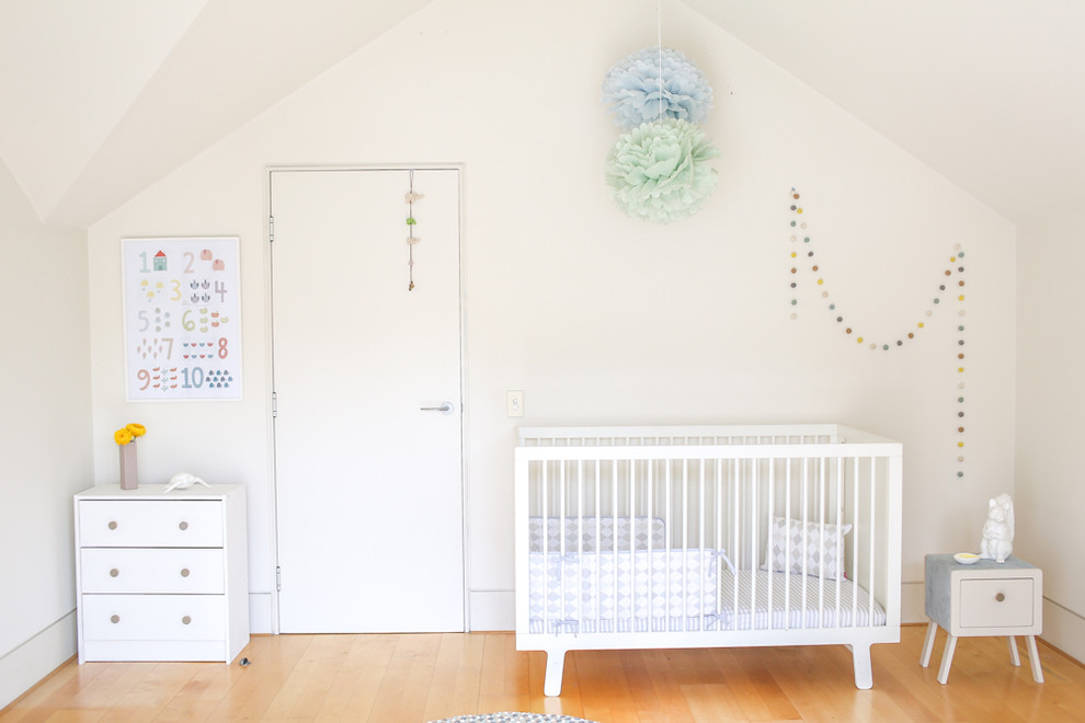 Idées déco pour une chambre de bébé neutre contemporaine de taille moyenne avec un mur blanc et parquet clair.
