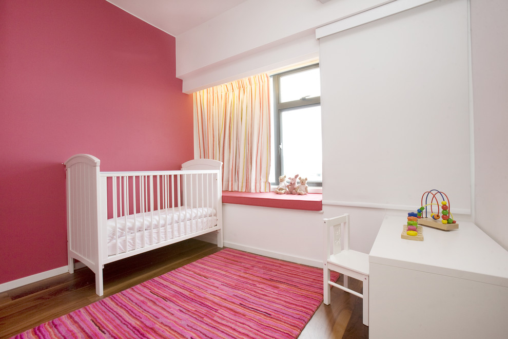 Photo of a medium sized contemporary nursery for girls in Hong Kong with pink walls and medium hardwood flooring.