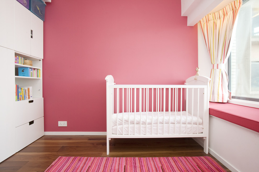 На фото: комната для малыша среднего размера в современном стиле с розовыми стенами и паркетным полом среднего тона для девочки